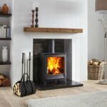 Black log carrier bag with firewood next to a wood-burning stove