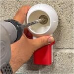 Drill dust collector held against a brick wall while drilling