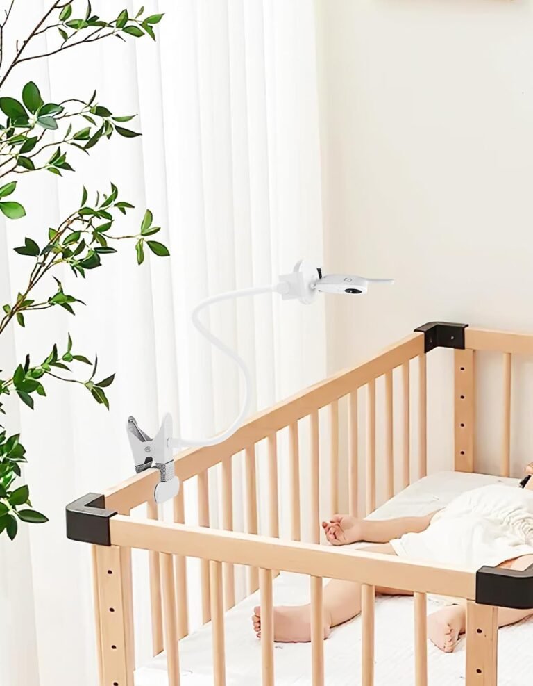 White flexible baby monitor holder clipped to a wooden cot in a nursery