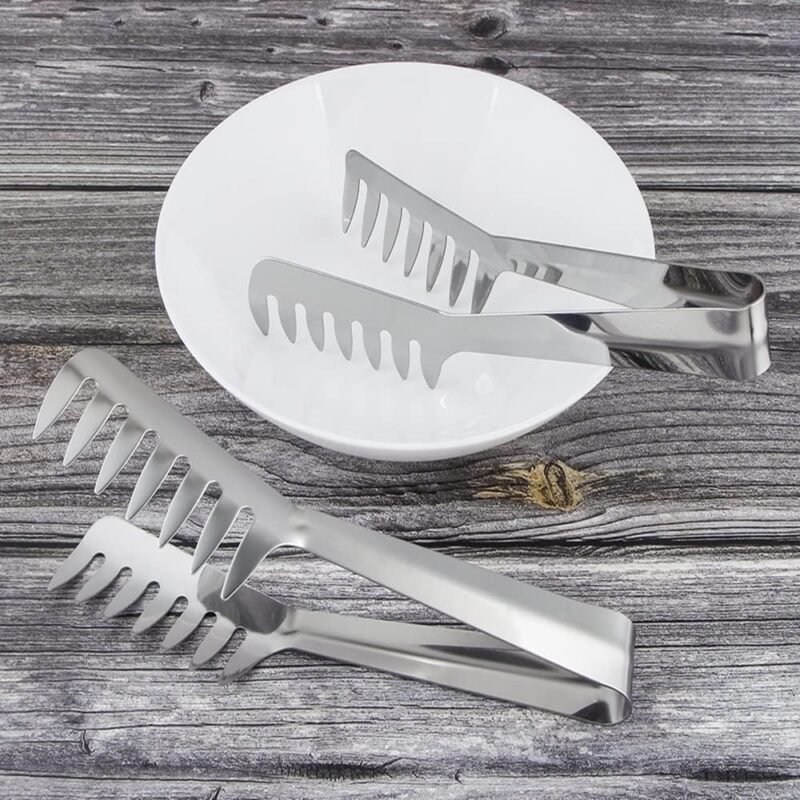 Stainless steel pasta tongs on a rustic wooden table