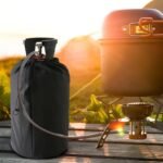 Black gas bottle cover on a cylinder outdoors next to a camping stove