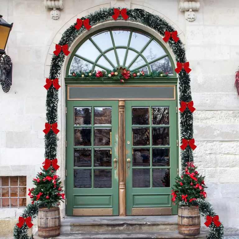 Green tinsel garland with red bows framing a front door at Christmas