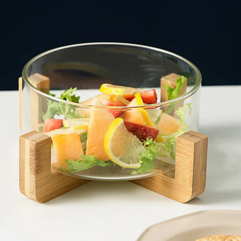 Glass bowl on a wooden stand filled with fruit salad on a dining table