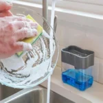 Washing-up liquid dispenser with sponge next to the kitchen sink while washing up
