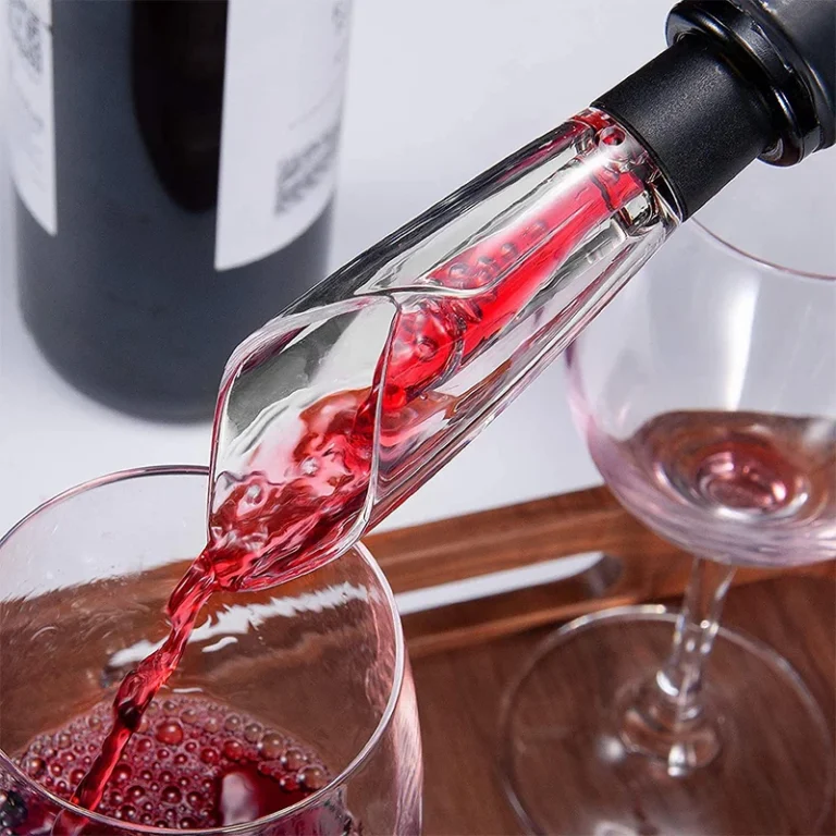 Aerating pourer pouring red wine into a glass on a wooden tray