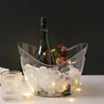 Clear acrylic ice bucket filled with ice and bottles on a table