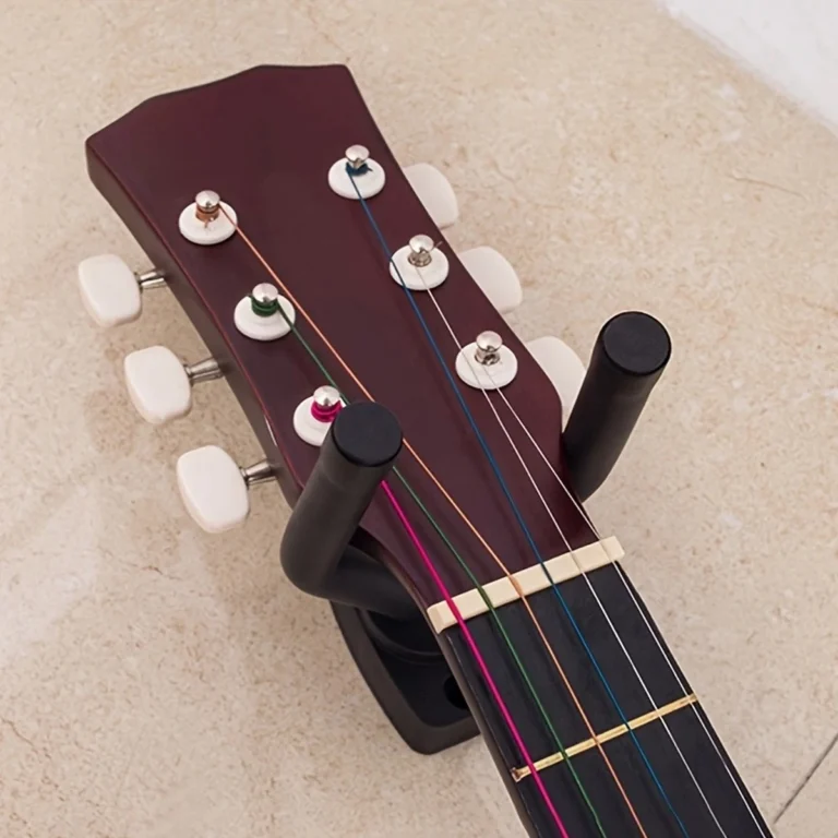 Black wall-mounted guitar hanger holding an acoustic guitar