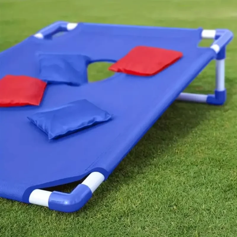 Blue bean bag toss board with bean bags on a lawn