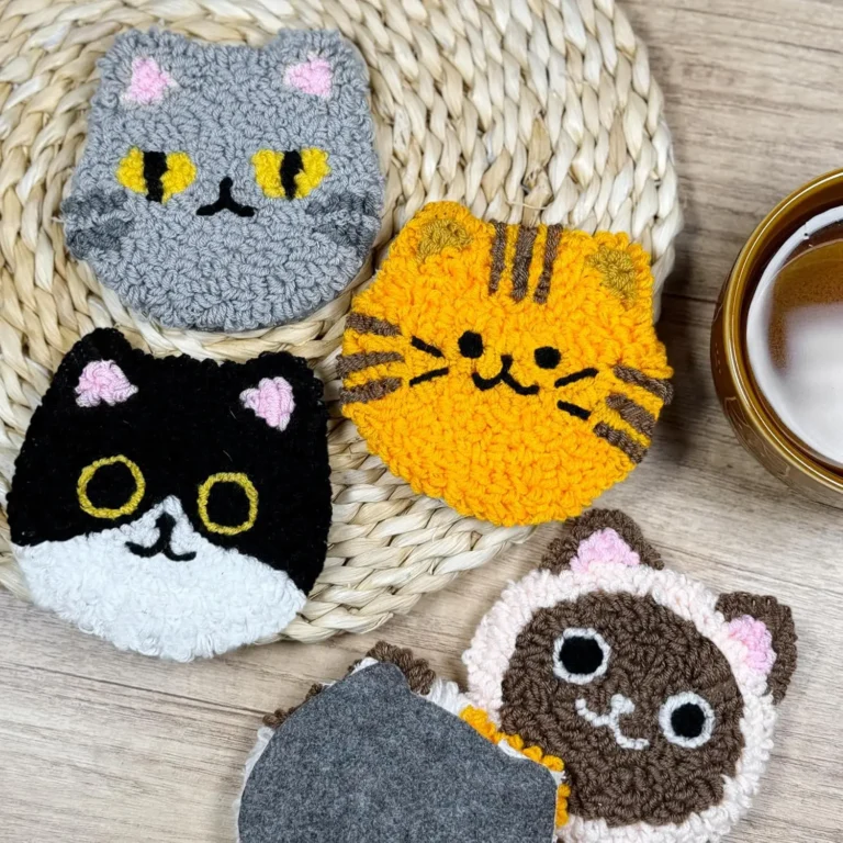 Finished punch needle cat coasters on a woven placemat next to a cup of tea