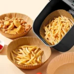 Round air fryer paper liners filled with chips and nuggets next to an air fryer