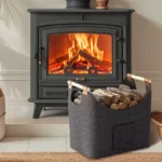 Dark grey felt log basket with wooden handles filled with firewood beside a wood stove