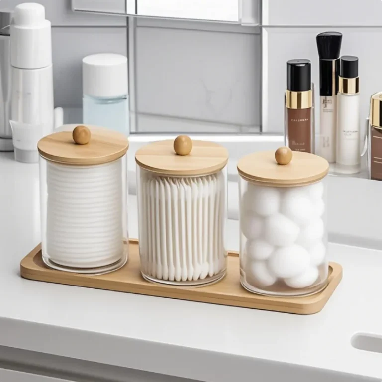 Three acrylic jars with wooden lids on a bamboo tray on a bathroom counter