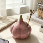 Pink garlic-shaped ceramic jar with lid on a kitchen worktop