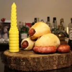 Yellow hot dog bun tool on a wooden board with sausages in buns