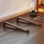 Two wooden laptop stand pieces on a desk by a window