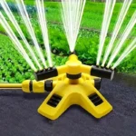 Yellow rotating garden sprinkler watering a vegetable bed