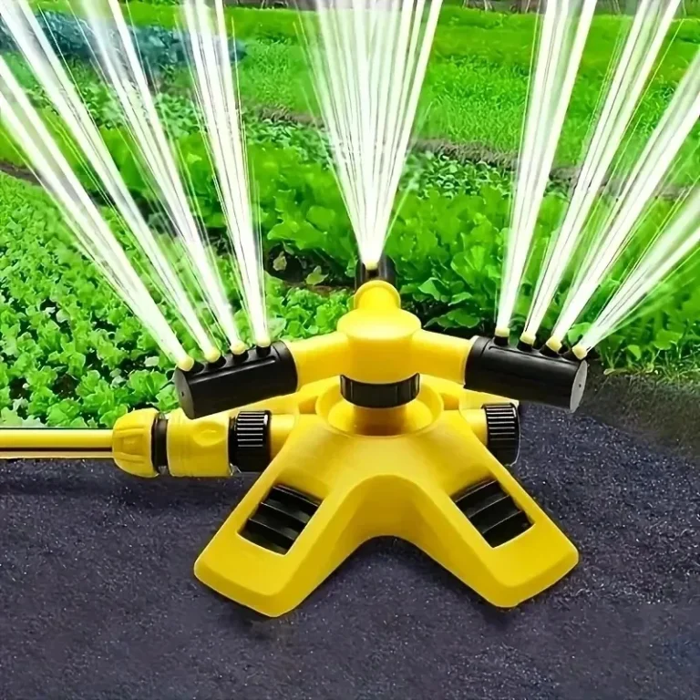 Yellow rotating garden sprinkler watering a vegetable bed