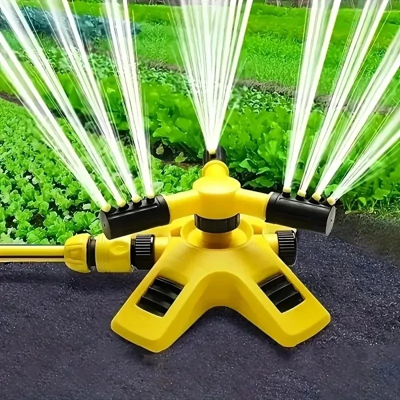 Yellow rotating garden sprinkler watering a vegetable bed