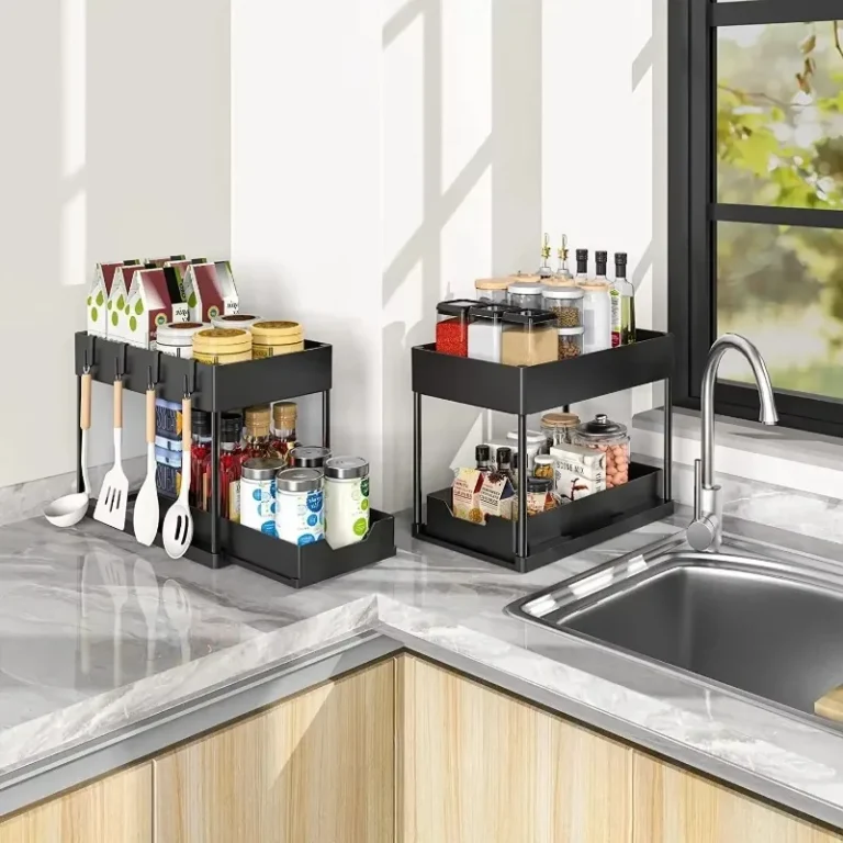 Two-tier black storage organiser holding spices and utensils on a kitchen worktop by the sink