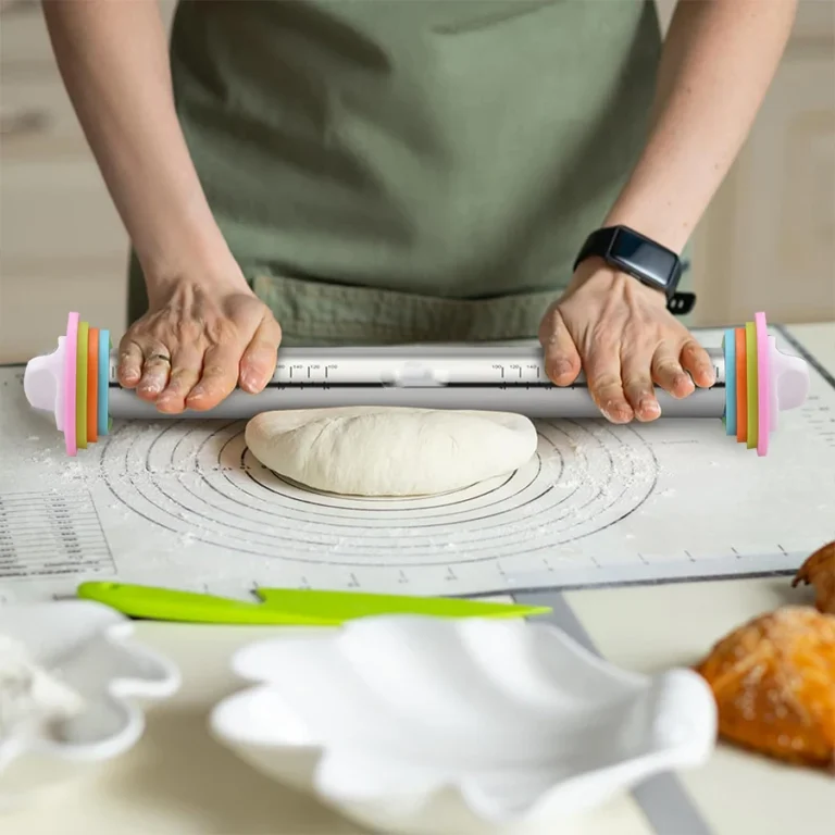 Stainless steel rolling pin with colourful thickness rings rolling dough on a baking mat