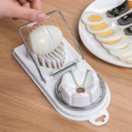 Two-in-one egg slicer slicing a boiled egg on a wooden table