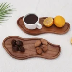 Two peanut-shaped wooden serving trays with coffee, lemons and nuts