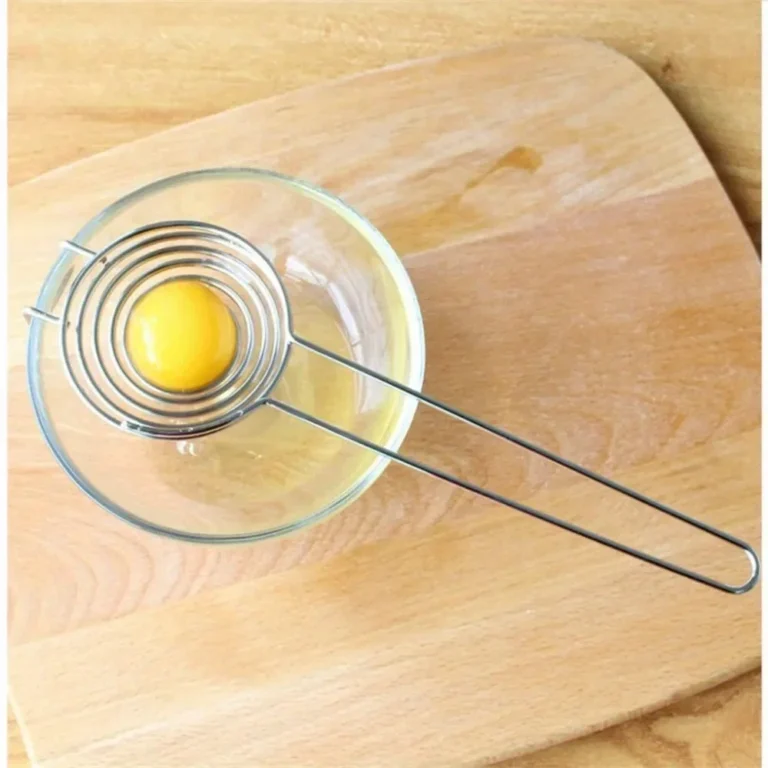 Spiral stainless steel egg separator over a glass bowl on a chopping board