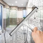 Chrome shower squeegee wiping a shower screen