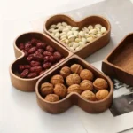 Heart-shaped walnut serving trays filled with nuts and dried fruit