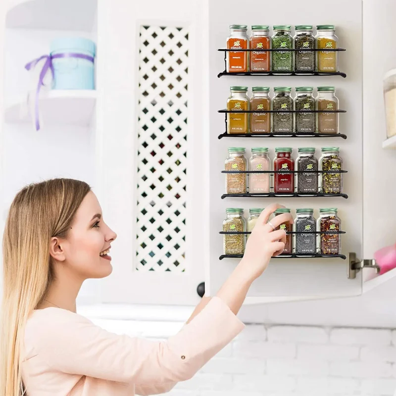 Black wall spice racks mounted on a kitchen cupboard door, filled with spice jars