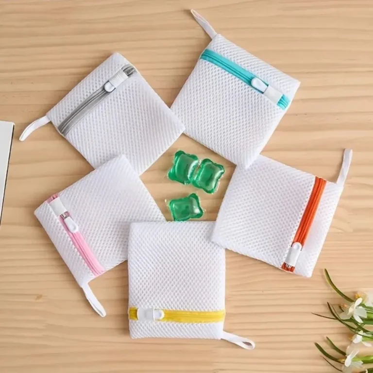 White mesh laundry bags with coloured zips on a wooden table
