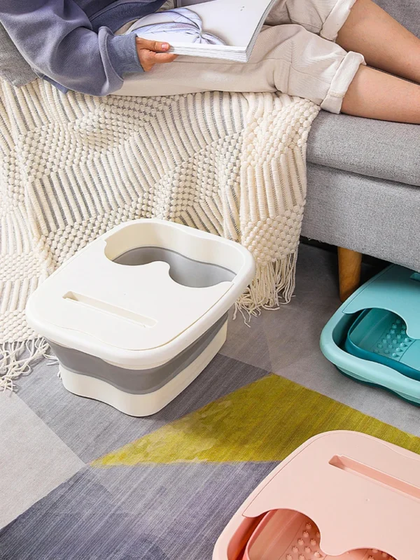 Foldable foot bath basins in white, blue and pink next to a sofa