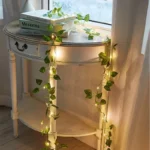 Artificial ivy fairy lights draped over a white side table