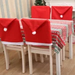 Red Santa hat covers on dining chairs at a festive table