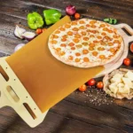 Sliding pizza peel with a pizza on a wooden kitchen table with fresh ingredients
