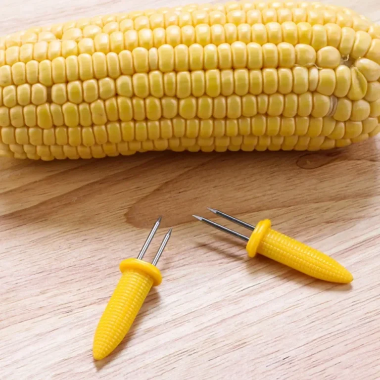 Yellow corn cob holder on a wooden table next to corn on the cob