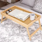 Foldable bamboo bed tray with a book and mug on a bed