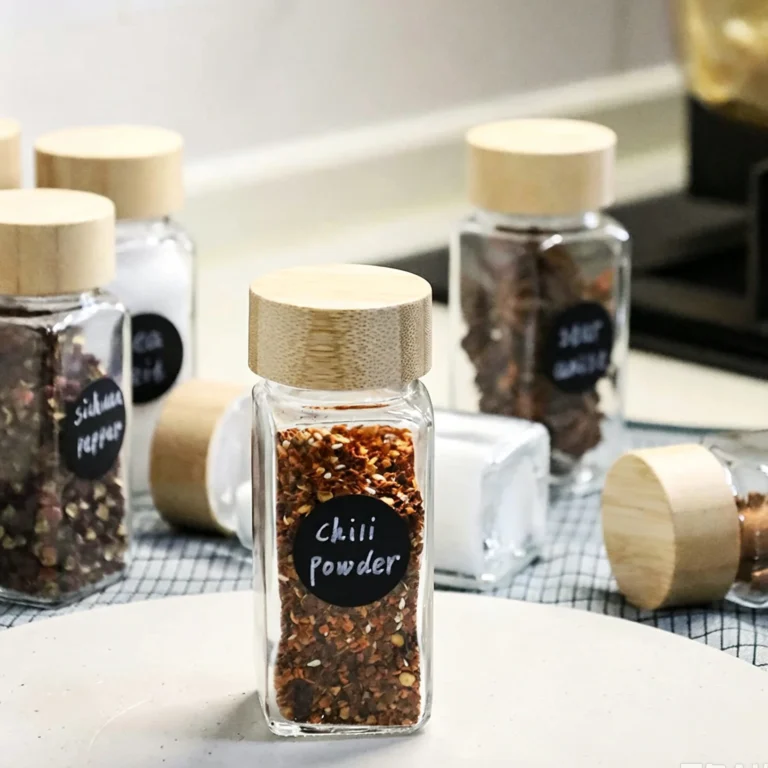 Glass spice jars with bamboo lids and chalkboard labels on a kitchen counter