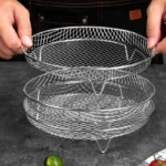 Round stainless steel mesh air fryer racks being stacked on a kitchen table