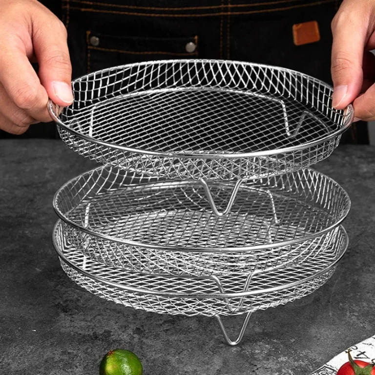 Round stainless steel mesh air fryer racks being stacked on a kitchen table