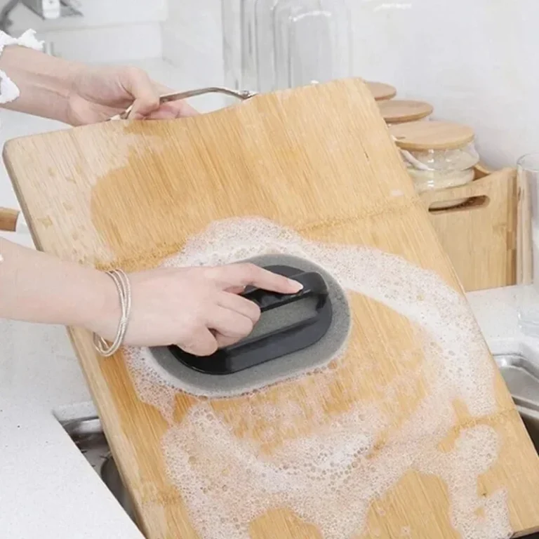 Sponge brush with handle scrubbing a wooden chopping board