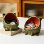 Two ceramic frog bowls with keys and sweets on a table