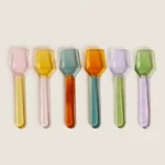 Coloured glass dessert spoons in a row