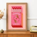 Framed matchbox poster on a sideboard