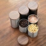 Steel canisters with wooden lids holding coffee, salt and tea