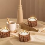 Three wooden tree-stump tealight holders with lit candles on a table