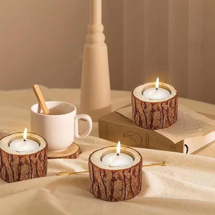 Three wooden tree-stump tealight holders with lit candles on a table